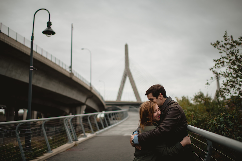 Chris and Katie embracing in front of a bridge